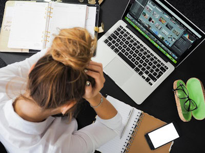 Selbstständig machen ohne Technikfrust – so findest du deinen klaren Weg 1 Eine Frau, mit dem Kopf in den Händen, vor einem PC sitzend, wirkt überfordert über die Aufgaben.